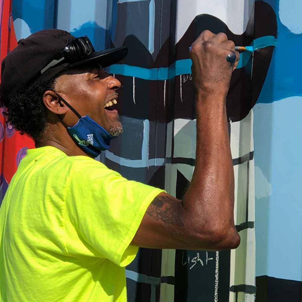 Man Painting Mural on Metal Wall