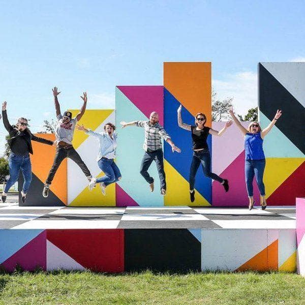 People Jumping in Front of Mural