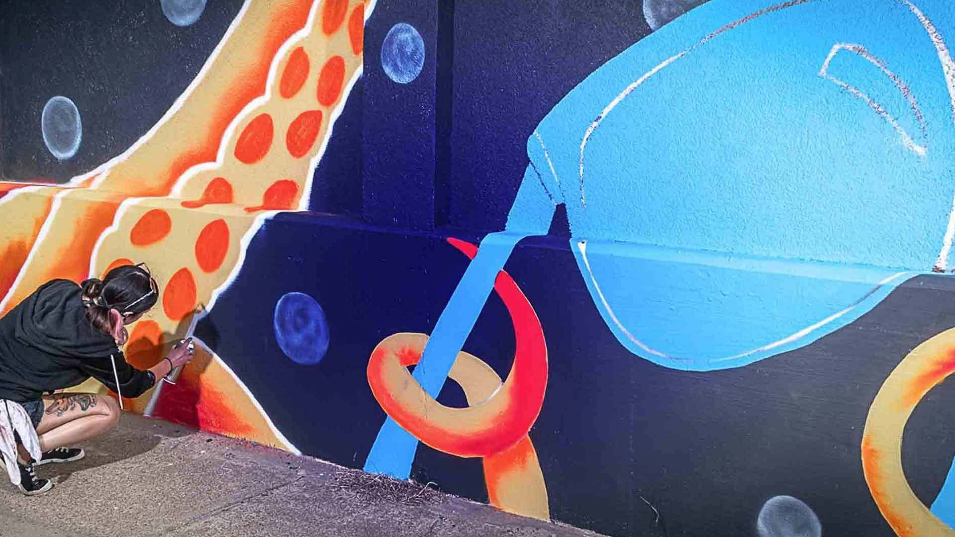 Female Artist Spray Painting Wall